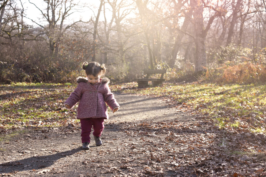 Little girl walking on a forest path in autumn light in New Jersey