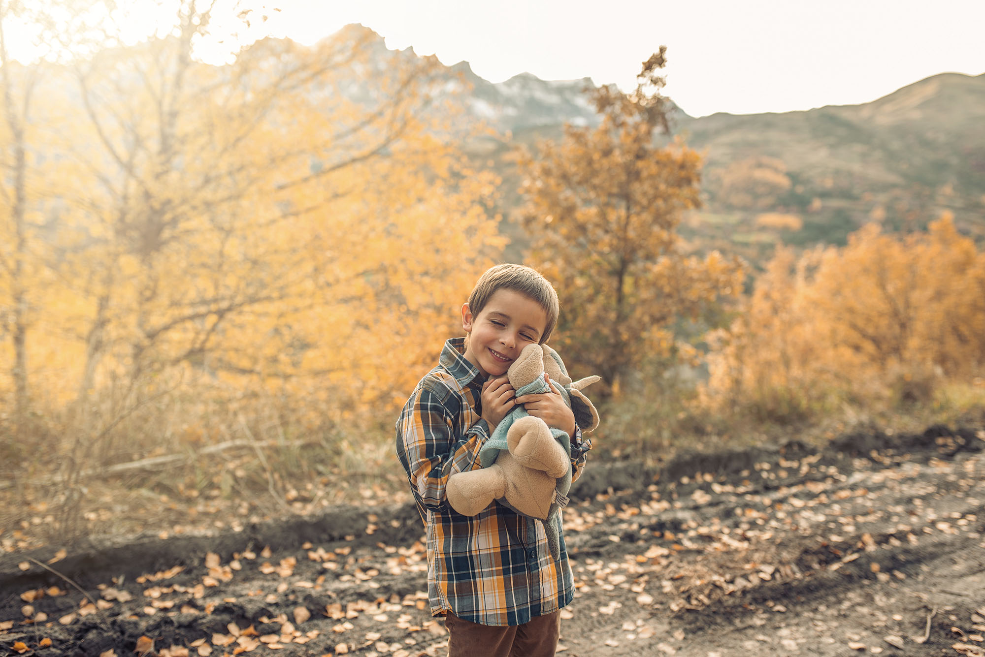 Little boy hugging his favorite stuffed animal in an outdoor family photography session in the woods.