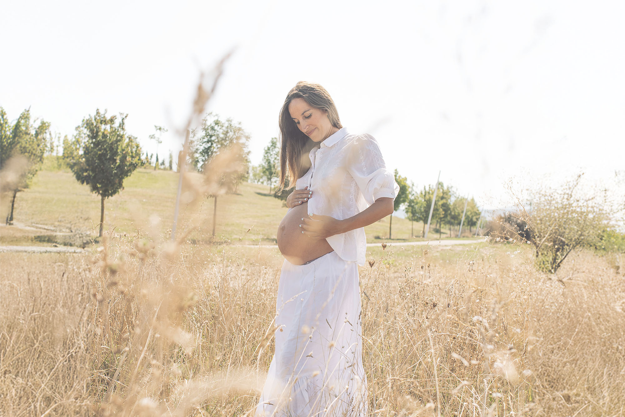 The beauty of the woman during the pregnancy in soft light standing in a natural field