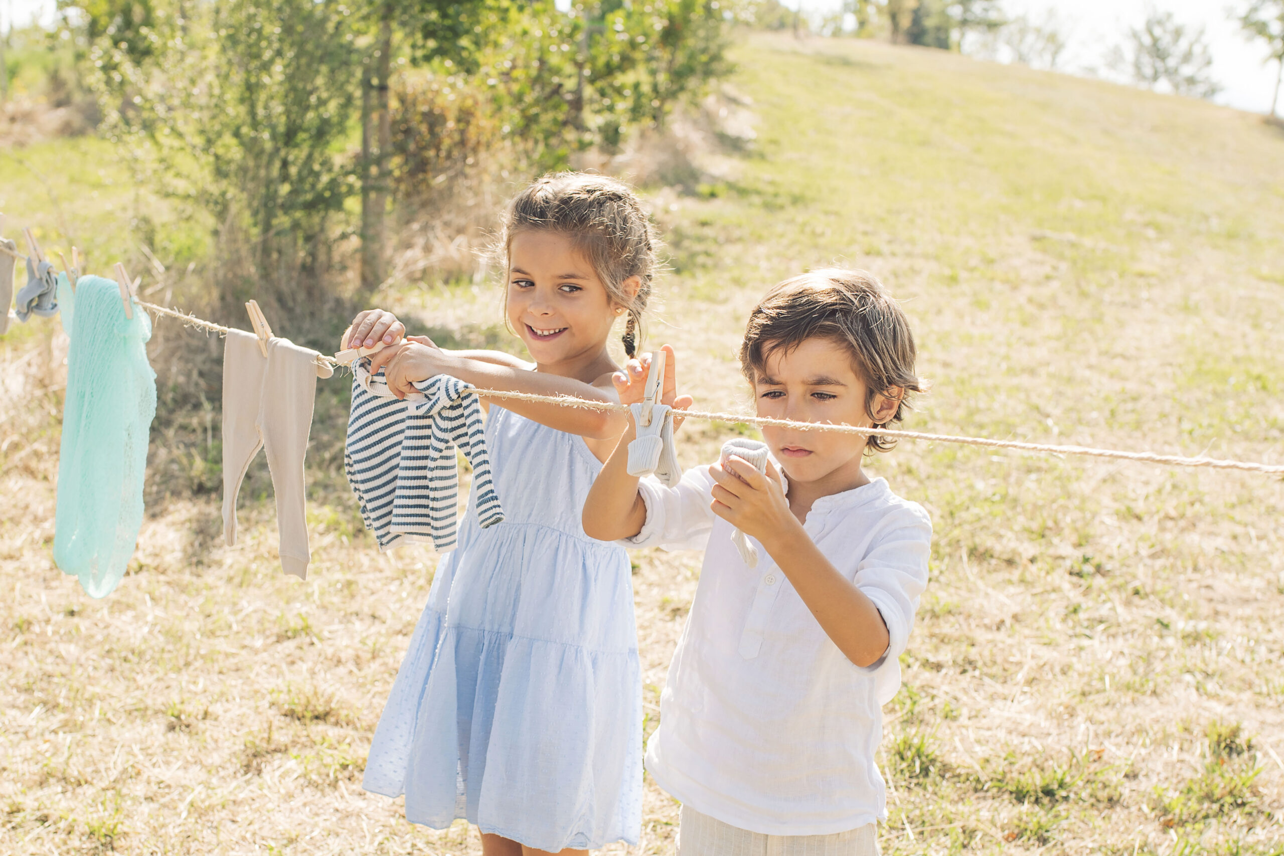 Siblings hanging their baby broyher clothes during outdoor maternity session