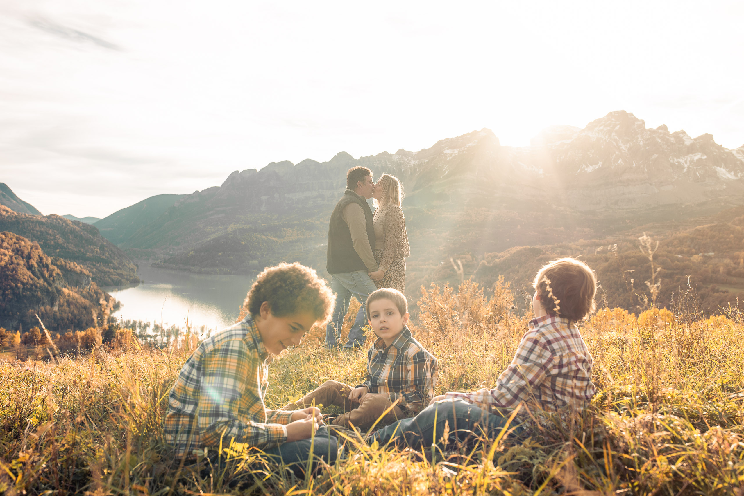Children sitting in the grass with parents in the background at sunset
